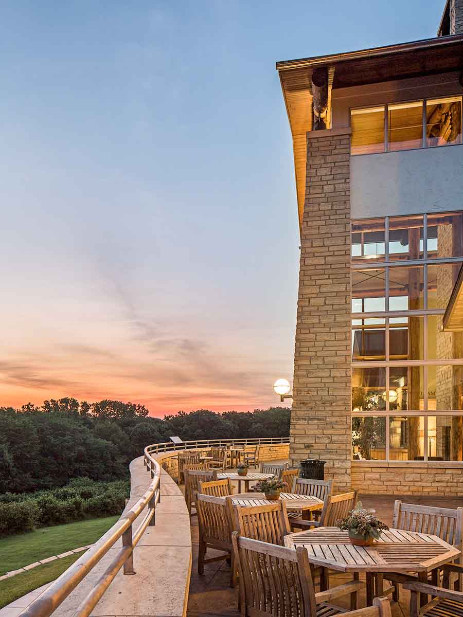 A picturesque outdoor view of the Lied lodge with wooden tables and sunset views