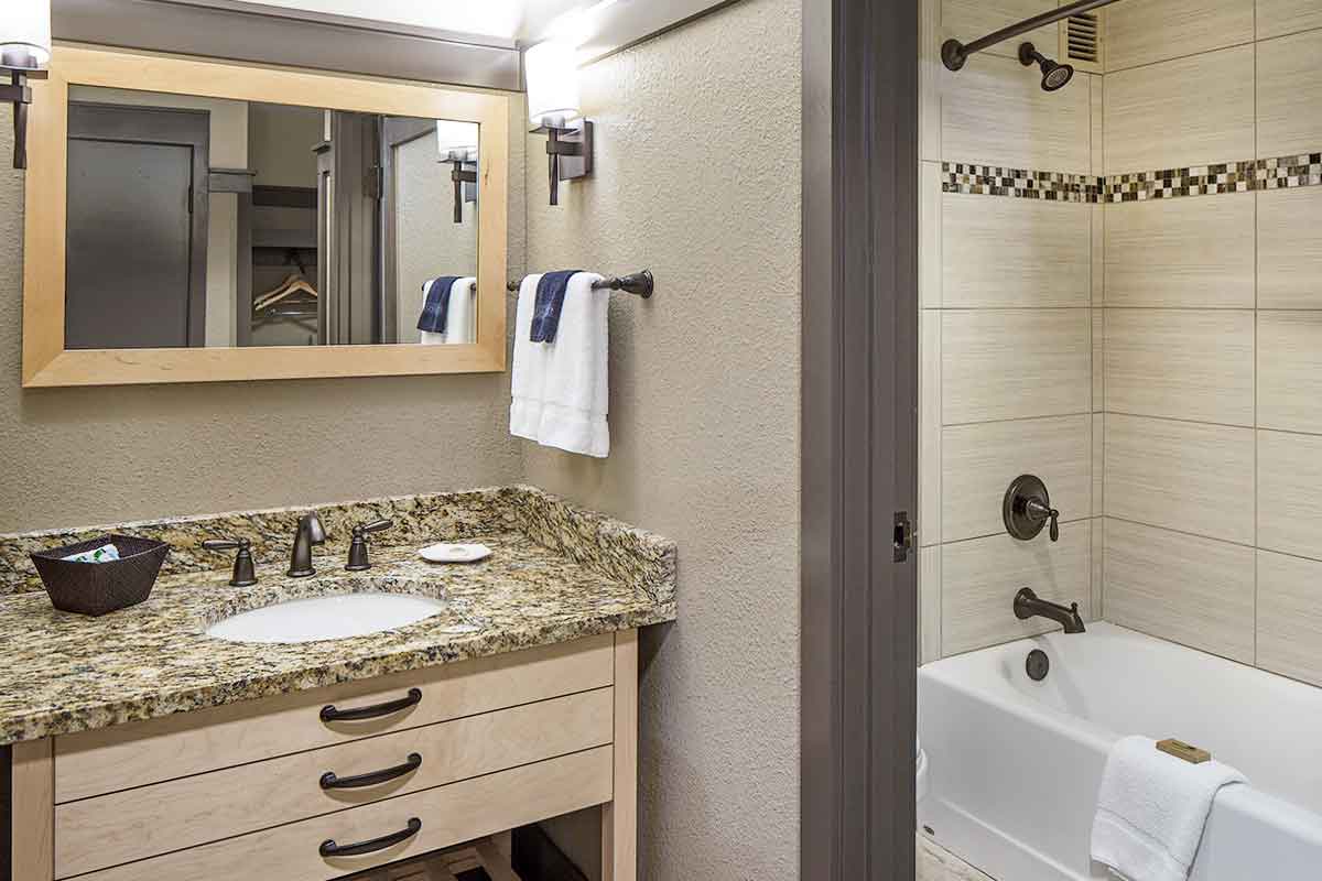a luxurious bathroom with a vanity, sink, drawers, shower and bath with towels and soaps