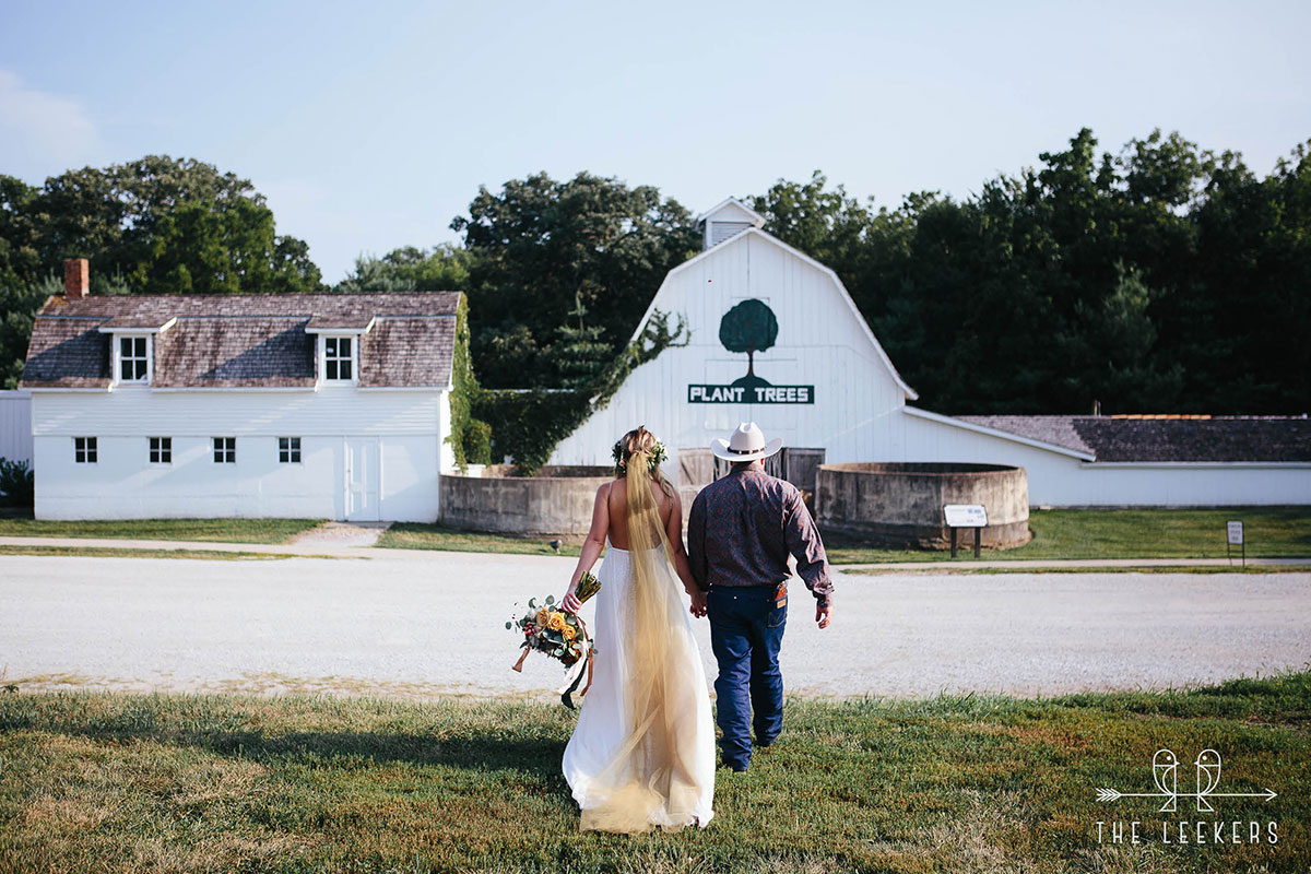 Bride and Groom Walk Towards Historic Barns