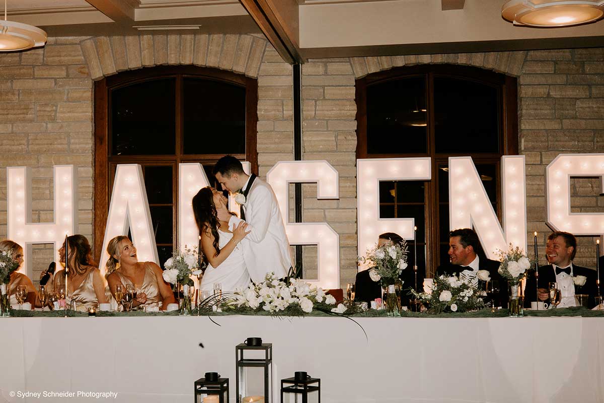 A Bride and Groom Embrace at their Head Table