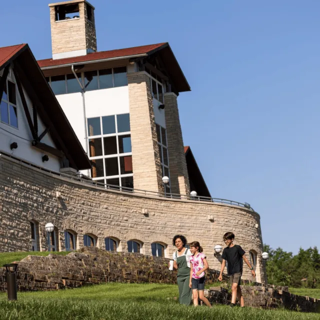 Family walking outside on a nice day with a lodge and blue skies. 