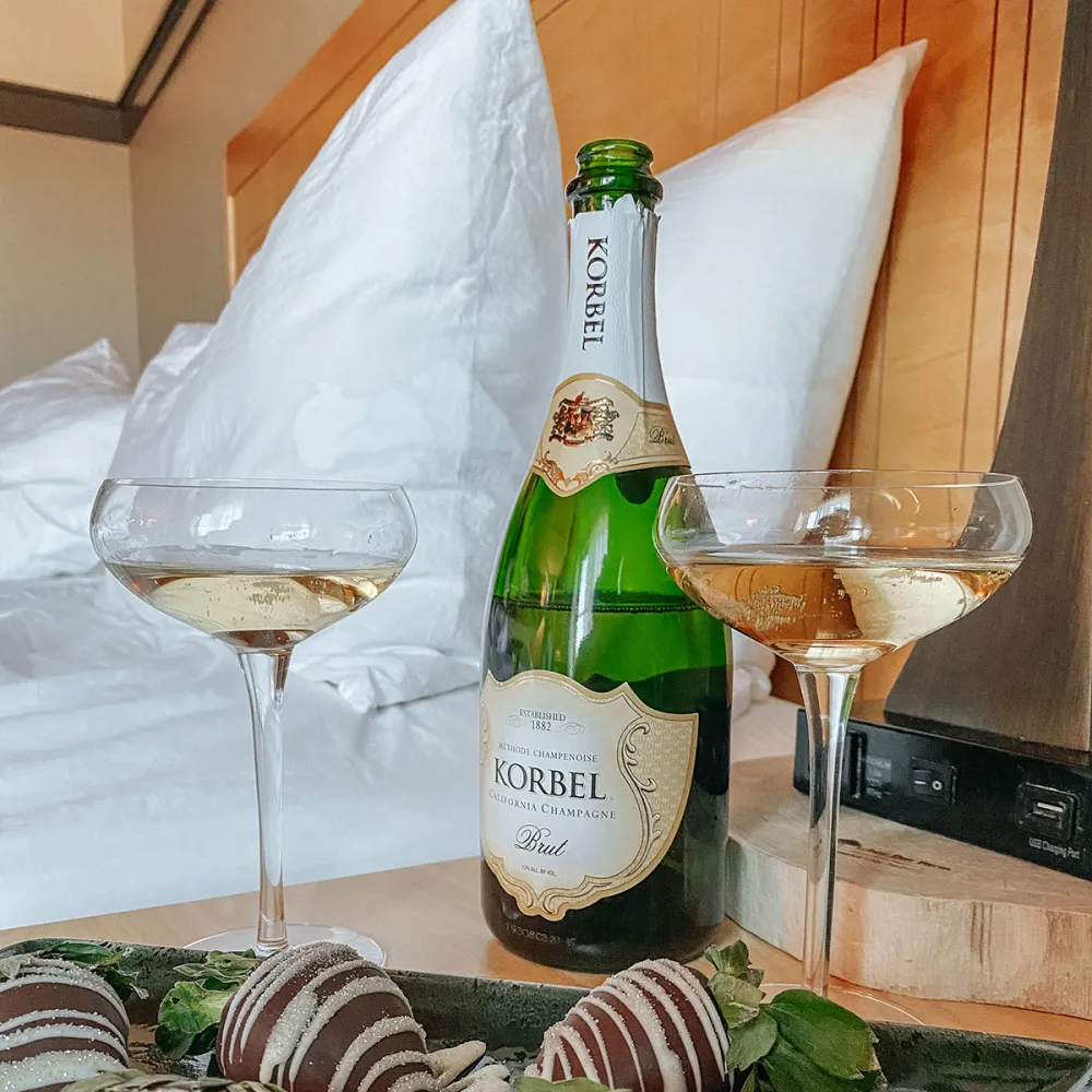 A bottle of champagne and fresh strawberries elegantly arranged on a decorative tray.