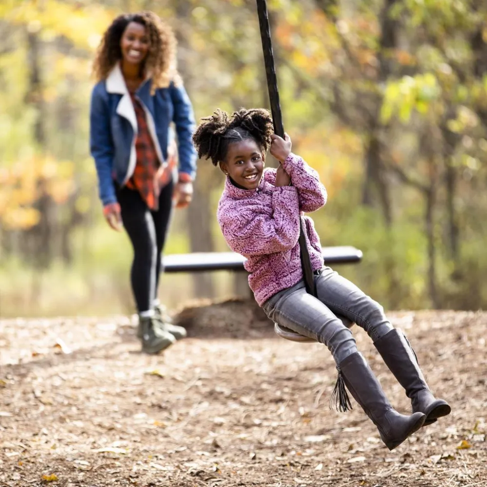 Mom and daughter outdoors interacting with a zip line on a nice fall day.