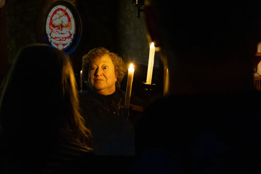 A woman standing in the dark holding a candle