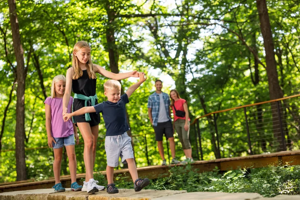 Kids playing outside surrounded by trees.