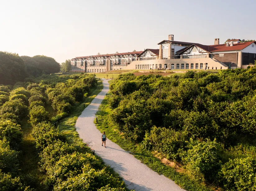 An overhead view of a person walks along a path next to the Lied Lodge, with nature surrounding the area.