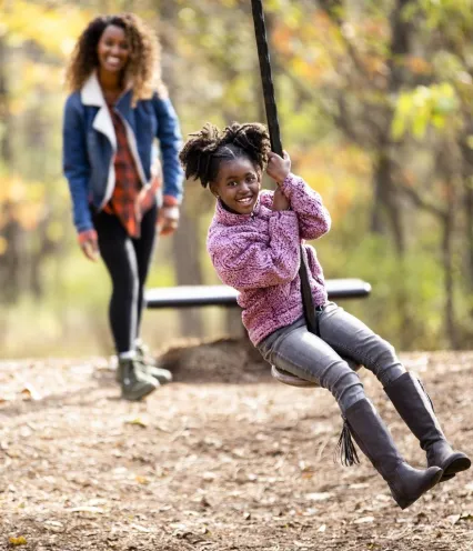 Mom and daughter outdoors interacting with a zip line on a nice fall day.
