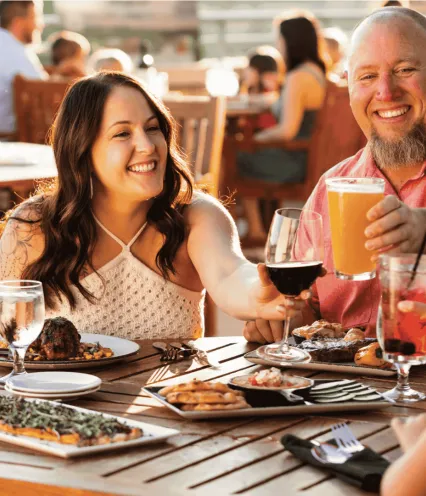 Couple dining outside and cheering with their drinks in the sunset.
