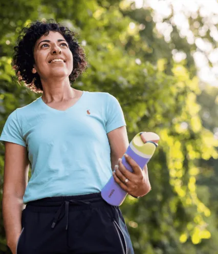 Women outside in athletic leisure clothing with water bottle smiling and hiking.