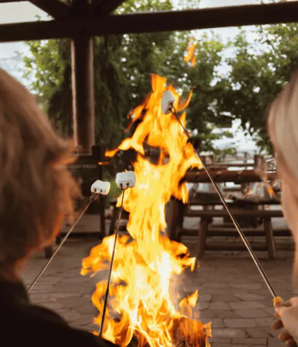 People sitting outdoors roasting marshmallows over a fire.