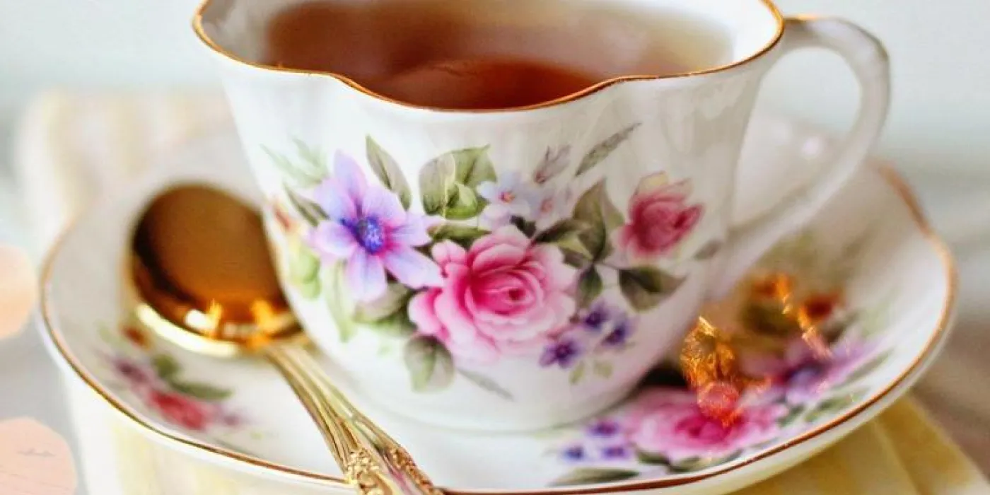 A delicate tea cup and saucer filled with steaming tea, set against a soft background, inviting for a cozy tea time.