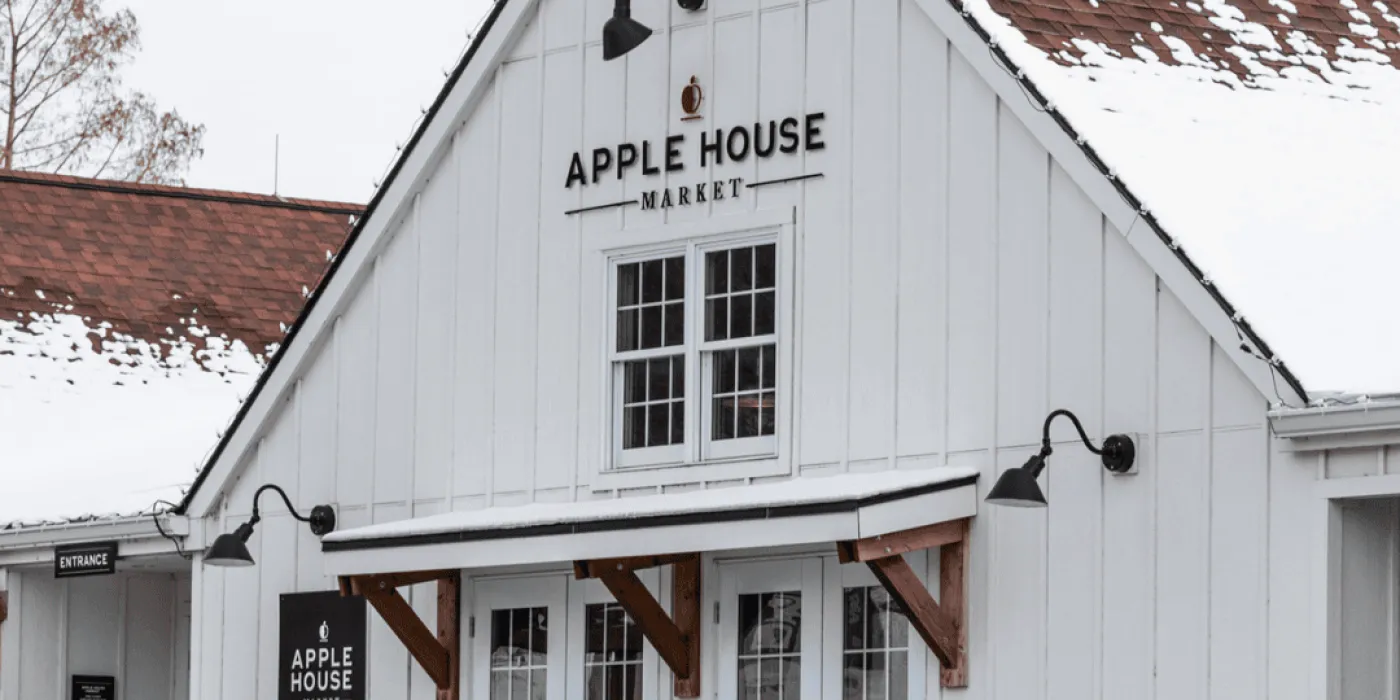 White building with a brown roof covered in snow that has begun melting. 