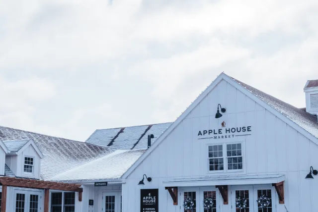 Exterior view of the Apple House Market, a modern white barn-style building with snow on the roof and ground.