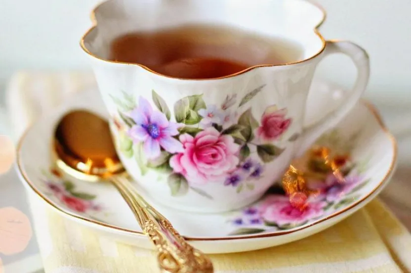 A delicate tea cup and saucer filled with steaming tea, set against a soft background, inviting for a cozy tea time.