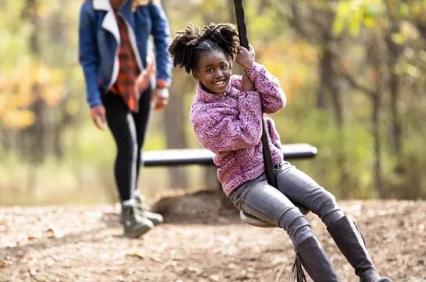 Mom and daughter outdoors interacting with a zip line on a nice fall day.