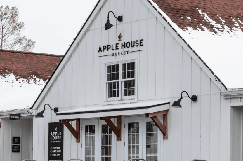 White building with a brown roof covered in snow that has begun melting. 