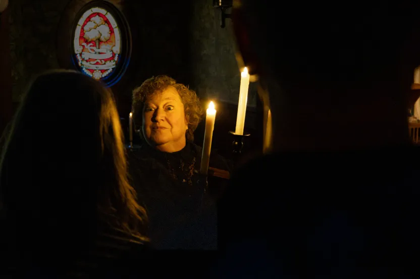 A woman standing in the dark holding a candle