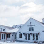 Exterior view of the Apple House Market, a modern white barn-style building with snow on the roof and ground.