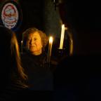A woman standing in the dark holding a candle